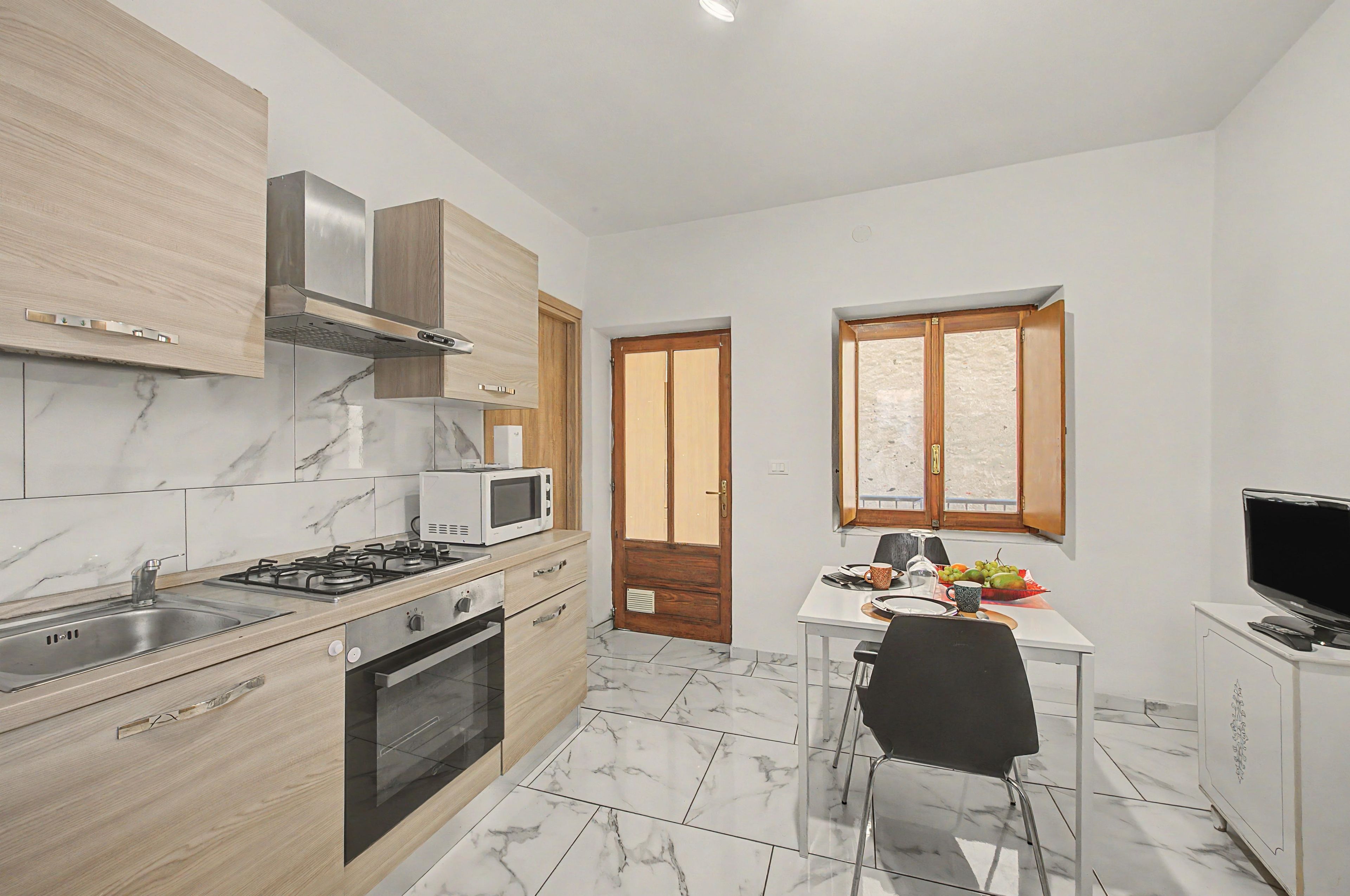 A compact kitchen with a gas stove, microwave, and wooden cabinets.