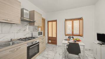 A compact kitchen with a gas stove, microwave, and wooden cabinets.