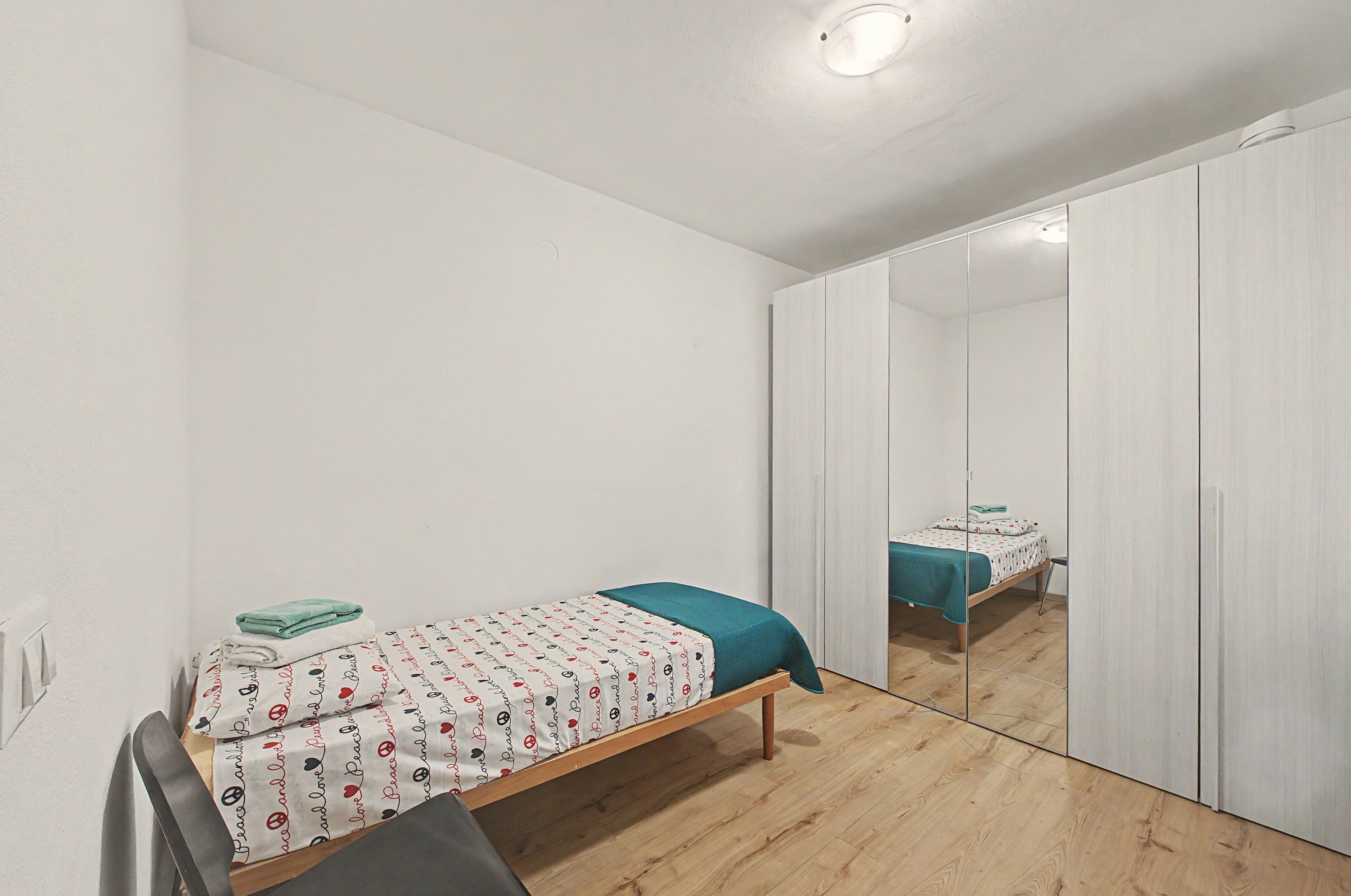 Une chambre à coucher avec un lit, un miroir et une armoire.