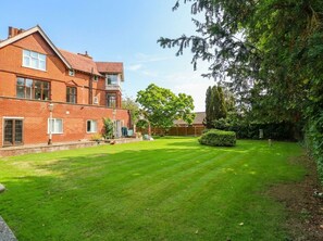 A residential property with a well-maintained lawn, a brick house, and a large tree. - Heritage Hideaway (Norwich)
