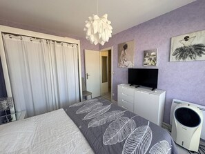 A bedroom with a bed, a TV, a dresser, and a radiator. - 42-square-meter apartment, 1 bedroom, downtown, parking (Aix-les-Bains)