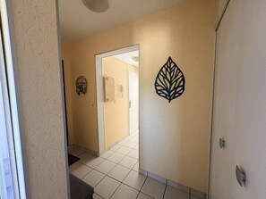 A hallway with a door leading to another room, a wall-mounted decorative item, and a tiled floor. - 42-square-meter apartment, 1 bedroom, downtown, parking (Aix-les-Bains)