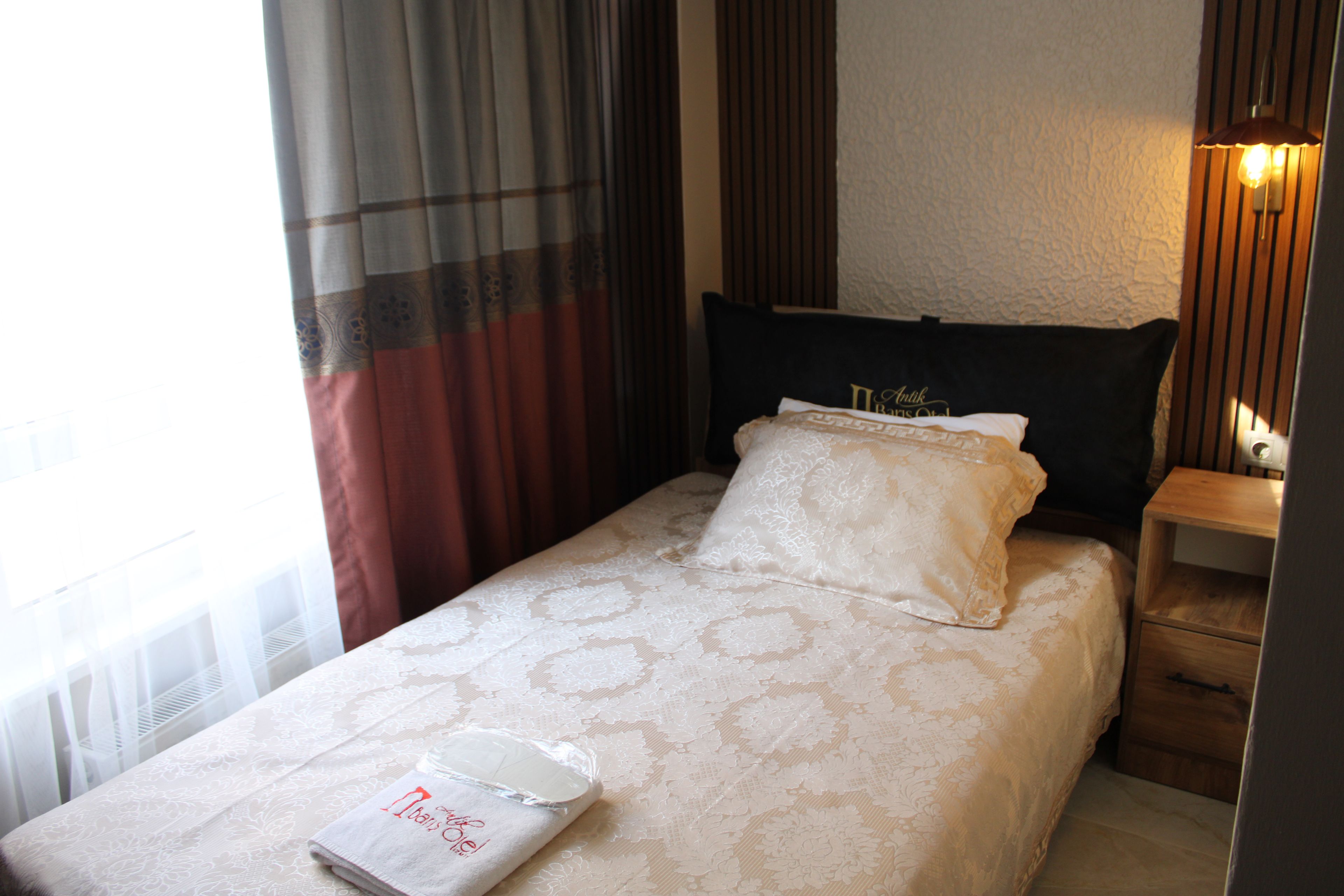 A neatly made bed with a white bedspread and a pillow with a monogram.