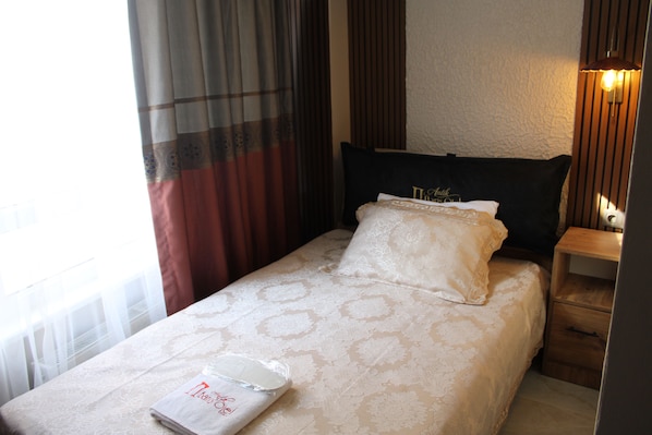 Una cama bien hecha con una colcha blanca y una almohada con un monograma.