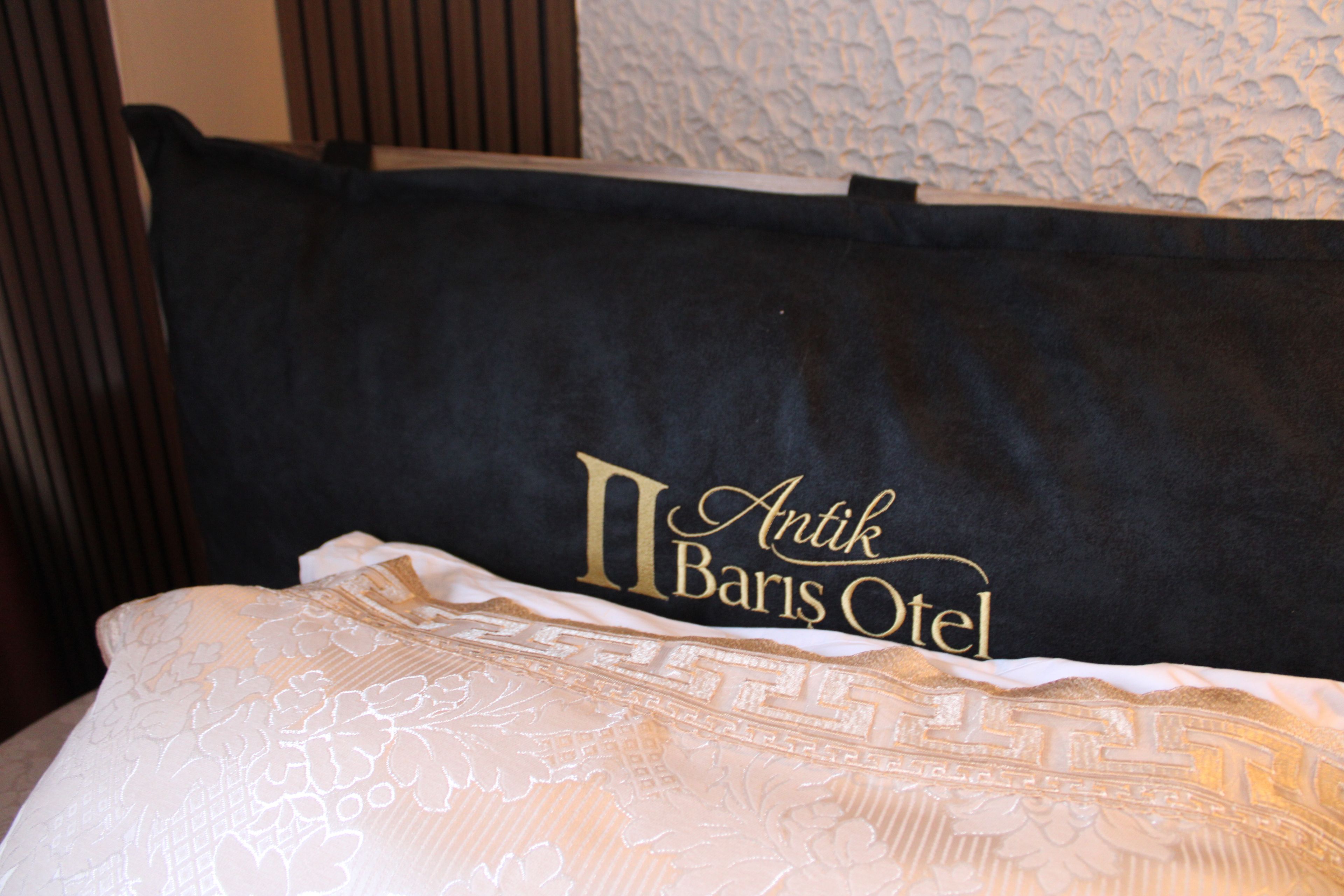 Ein Bett mit einem schwarzen Kopfkissen und einer goldbestickten Schrift.