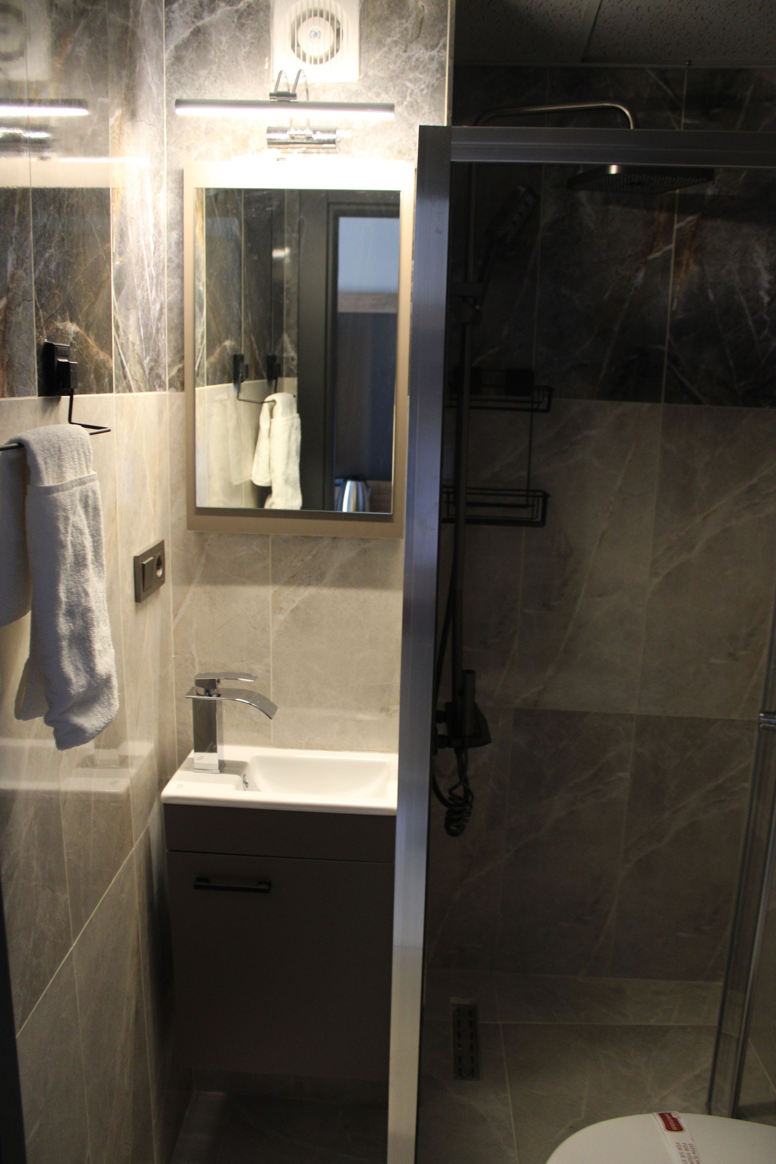 Un bagno con lavandino, specchio, portasciuga e doccia.
