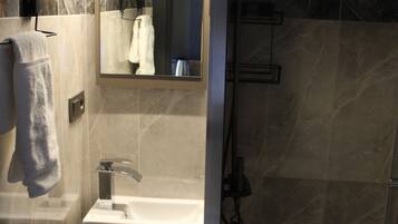 Un bagno con lavandino, specchio, portasciuga e doccia.