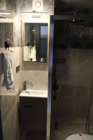 A bathroom with a sink, mirror, towel rack, and shower.