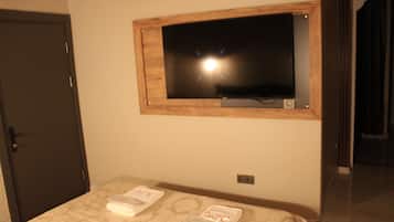A hotel room with a bed, a television mounted on the wall, and a door.