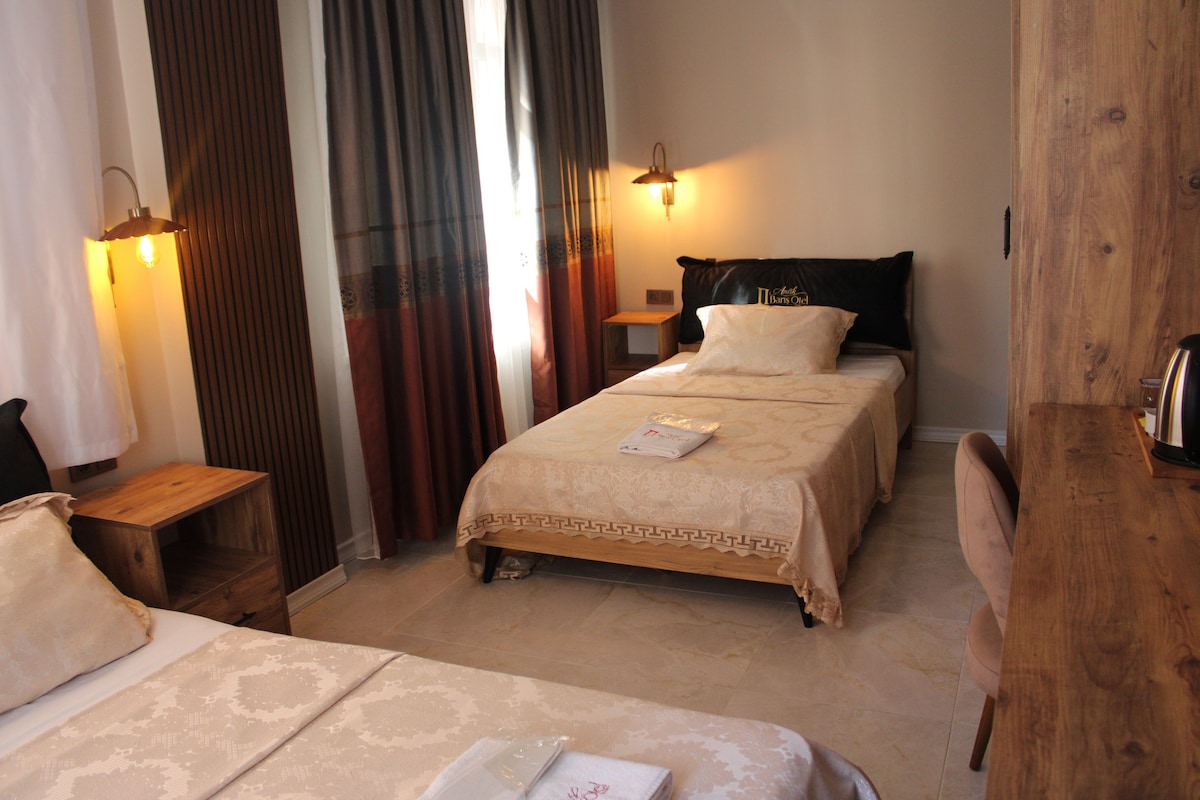 A hotel room with a double bed, a bedside table, a nightstand, a lamp, and a wooden headboard.