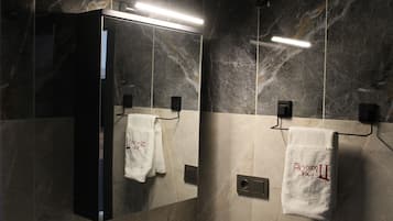 Un baño con un espejo, dos percheros y una lámpara.