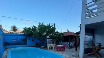 Una piscina con un patio de piedra, una pequeña mesa y una silla.