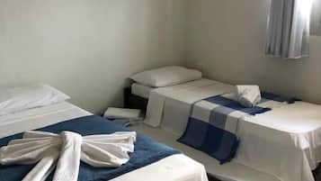 A hotel room with two beds, a bathroom, and a window with curtains.