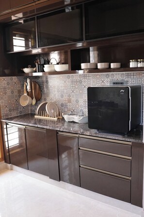Et moderne køkken med mørke skabe, et sort køleskab og et mønstret backsplash.