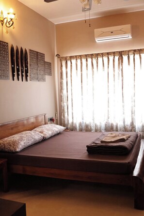 A bedroom with a bed, curtains, wall art, and an air conditioning unit. - Premium 2-Bedroom Apartment in Mysuru | Parking & WiFi (Mysuru)