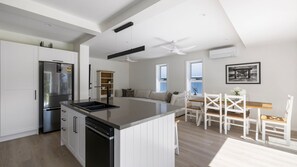 A modern kitchen with a central island, white cabinetry, and a built-in dishwasher. - Three Bays Retreat- Pet Friendly (Nelson Bay)