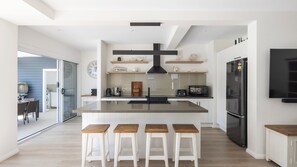 A modern kitchen with a central island, bar stools, a large stove, and a built-in oven. - Three Bays Retreat- Pet Friendly (Nelson Bay)
