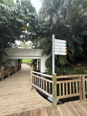 A wooden boardwalk leading to a signpost with directions to various amenities including a palace, restaurant, and fitness center. - Cozy 1-bedroom hotel suites with AC in cool Nuevo Vallarta, a lot of activities (Nuevo Vallarta)