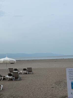 A beach with lounge chairs and umbrellas, a sign with text, and a calm sea in the background. - Cozy 1-bedroom hotel suites with AC in cool Nuevo Vallarta, a lot of activities (Nuevo Vallarta)