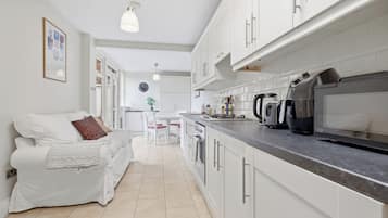 A modern kitchen with white cabinets, a countertop, and a kettle.