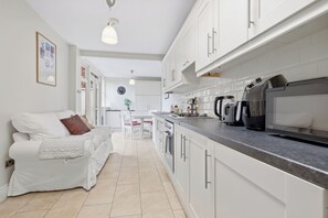 A modern kitchen with white cabinets, a countertop, and a kettle.