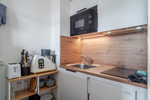 Una cocina compacta con microondas, tostadora y lavamanos.