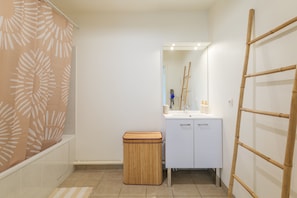 A bathroom with a white sink, mirror, and a wooden stool. - L'Escale Beauvaisienne - parking privé (Beauvais)