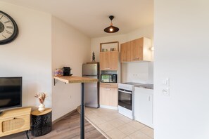 A compact kitchen with a microwave, oven, and a wooden cabinet with a sign. - L'Escale Beauvaisienne - parking privé (Beauvais)