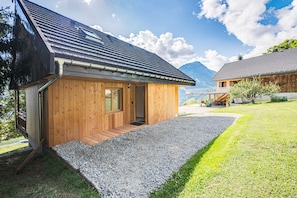 A wooden cabin with a gravel driveway, a wooden deck, and a mountain backdrop. - L'atelier - stations de ski à 10 min de voiture (Fontcouverte-la-Toussuire)