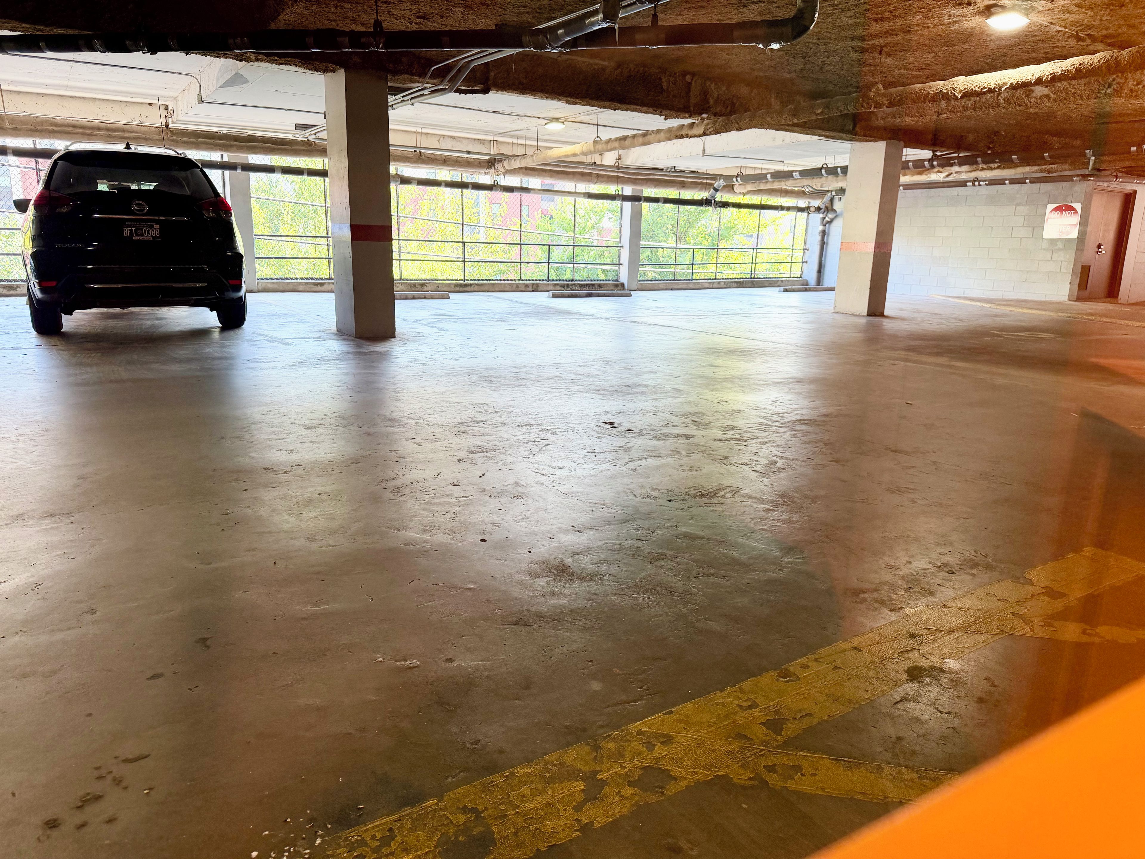 Een parkeergarage met een auto geparkeerd onder een betonnen pilaar.