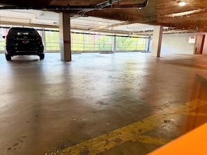 Een parkeergarage met een auto geparkeerd onder een betonnen pilaar.