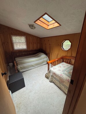 Ein Zimmer mit zwei Betten, einem Oberlicht und einem Fenster.