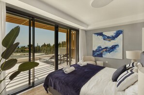 A modern hotel room with a large bed, a view of the outdoors, and a painting on the wall. - IIM Residences El Chaparral (Mijas)