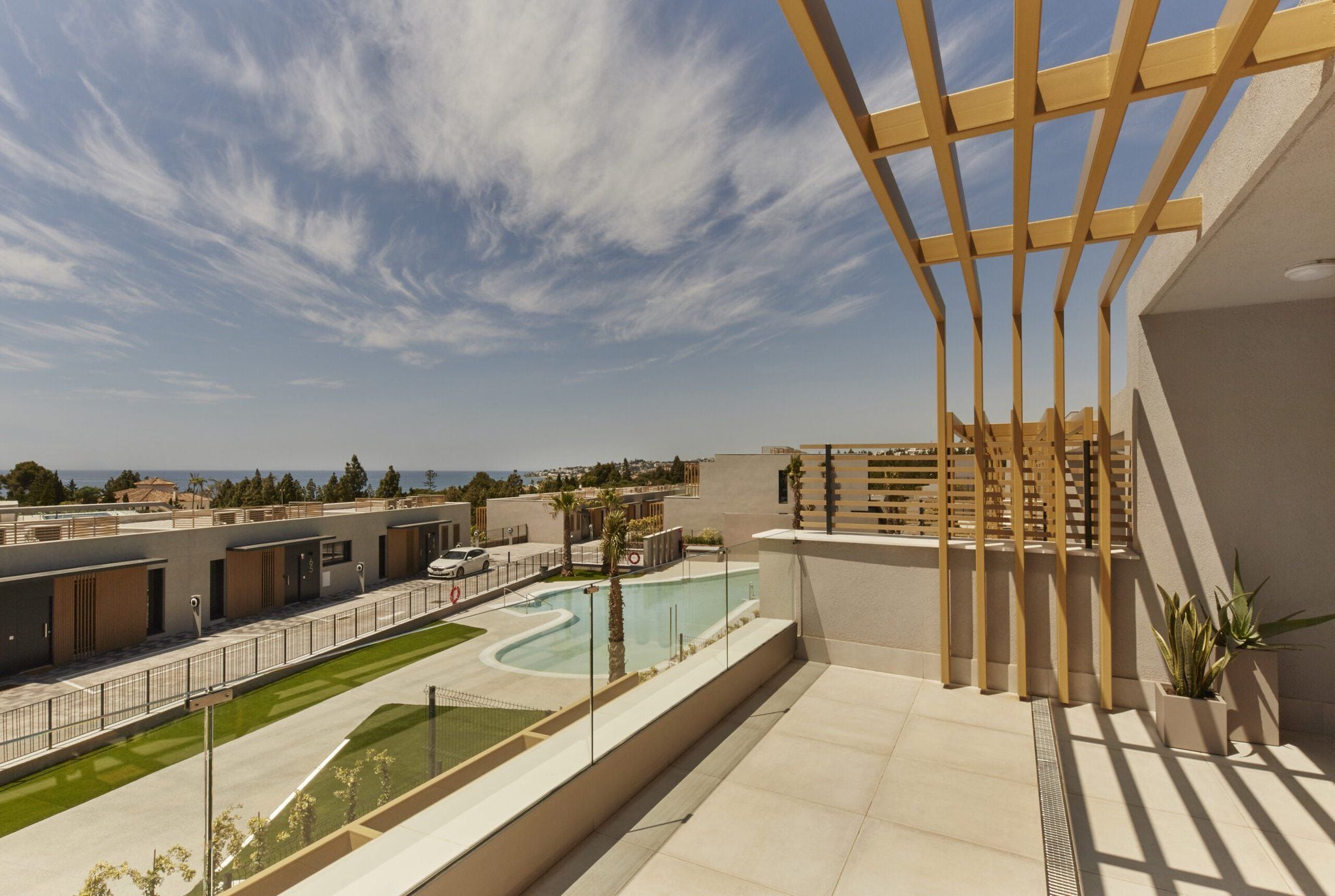 A rooftop terrace with a pool, a view of the sea, and a modern building structure.