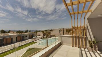 A rooftop terrace with a pool, a view of the sea, and a modern building structure.