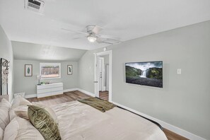 A bedroom with a bed, a ceiling fan, a dresser, a TV, and a door leading to another room. - Spacious 3BR Home with Full Kitchen and Carport (Abilene)