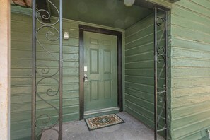 A green door with a metal gate, a doormat, and a small step leading to the entrance. - Spacious 3BR Home with Full Kitchen and Carport (Abilene)
