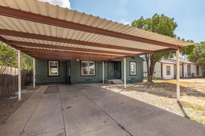 A house with a covered patio area, a fenced yard, and a neighboring house. - Spacious 3BR Home with Full Kitchen and Carport (Abilene)