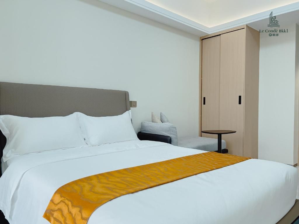 Una habitación de hotel con cama, mesita de noche, silla y armario.
