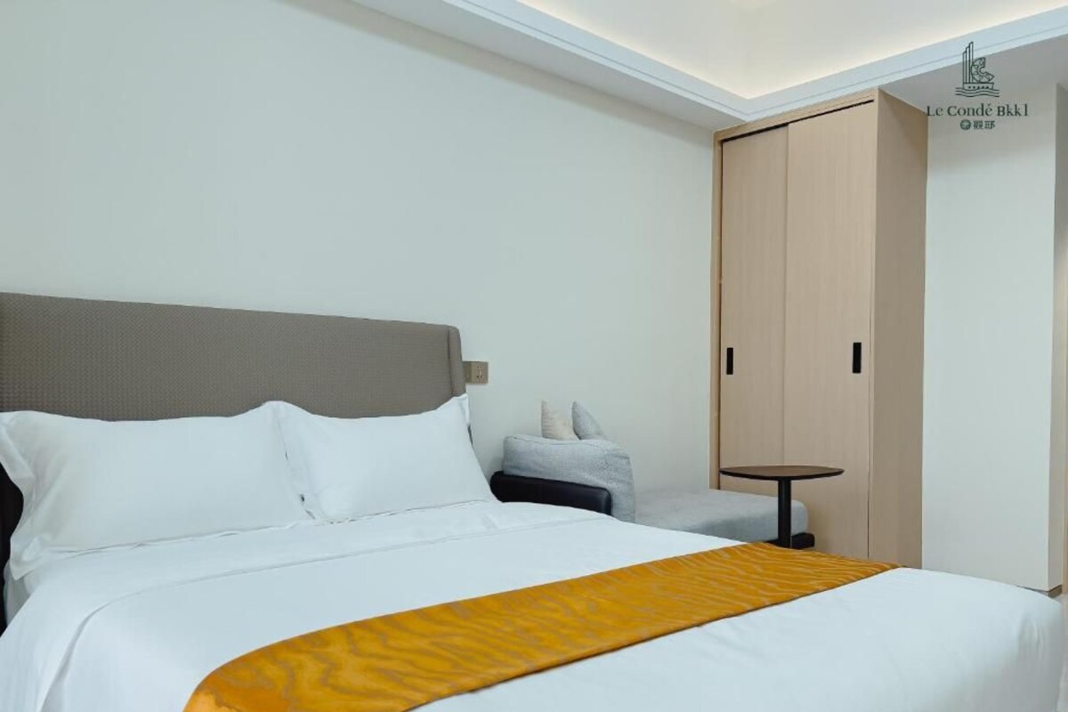 Una habitació d'hotel amb llit, una tauleta de nit, una cadira i un armari.