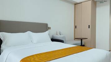 Een hotelkamer met een bed, nachtkastje, stoel en kledingkast.