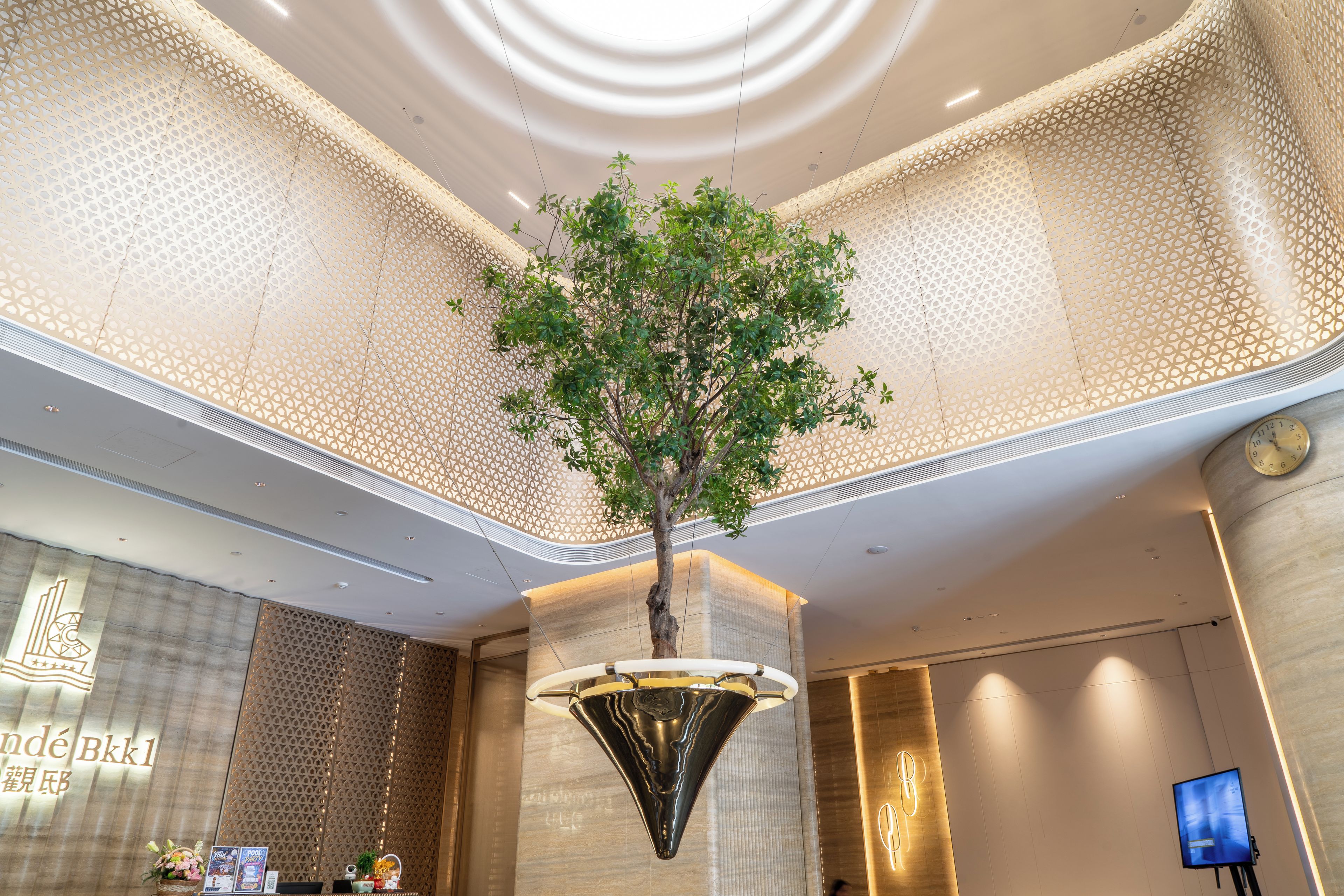 A lobby with a decorative tree, a reception desk, and a modern chandelier.