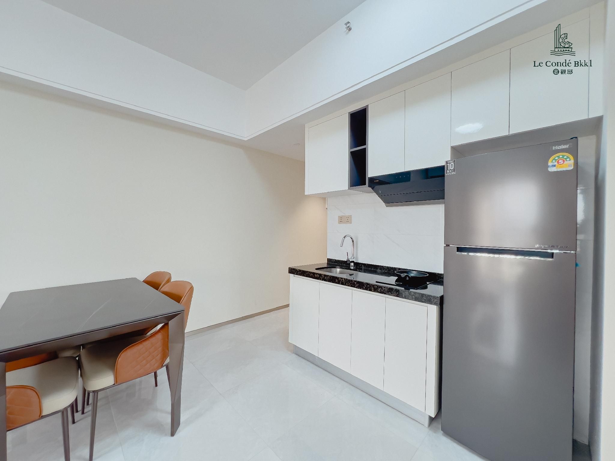 A modern kitchen with white cabinets, a stainless steel refrigerator, and a dining table with chairs.