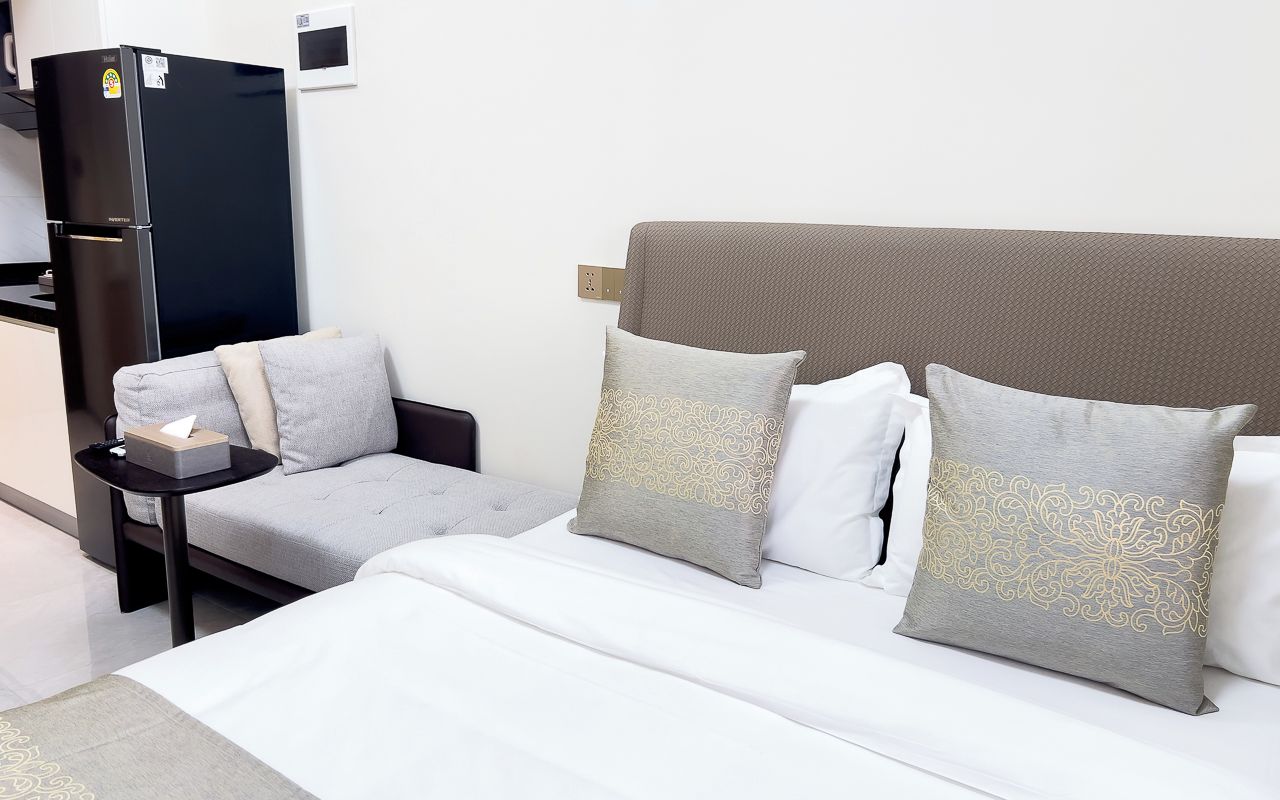 Una habitación de hotel con cama, sofá, una mesita y un refrigerador.