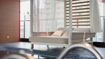 A modern room with a bed, a window with blinds, and a view of the city.