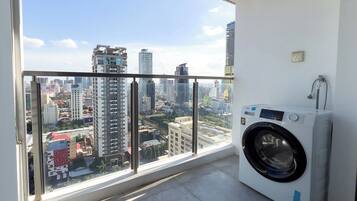 A balcony with a city view, a washing machine, and a power outlet on the wall.