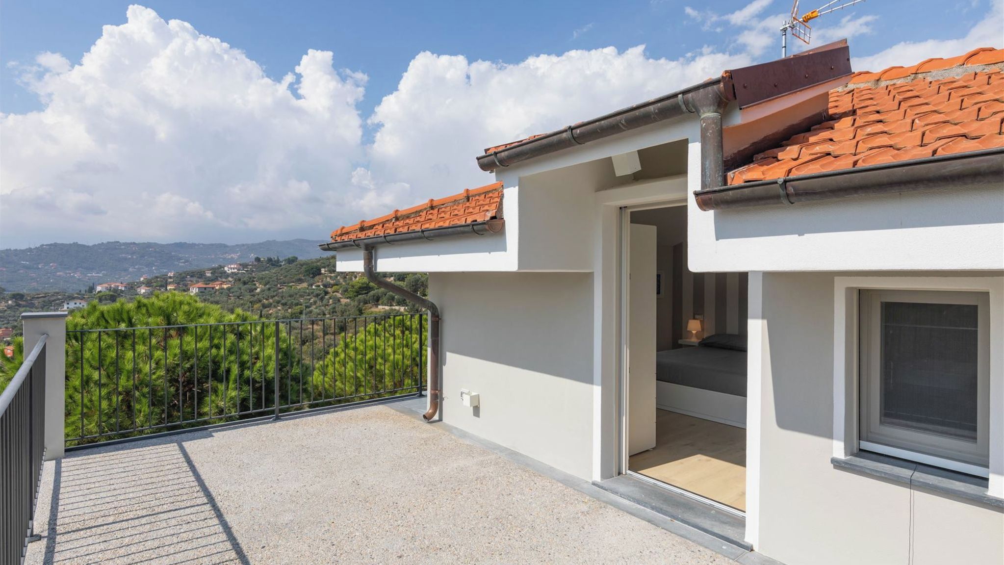 A balcony with a view of a hillside and distant buildings.