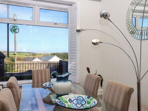 A dining area with a table set for four, chairs, a vase, and a view of the countryside through a window. - Angels Place (Yelverton)