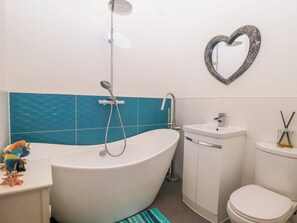A bathroom with a freestanding bathtub, a toilet, a sink, and a decorative heart-shaped mirror on the wall. - Angels Place (Yelverton)