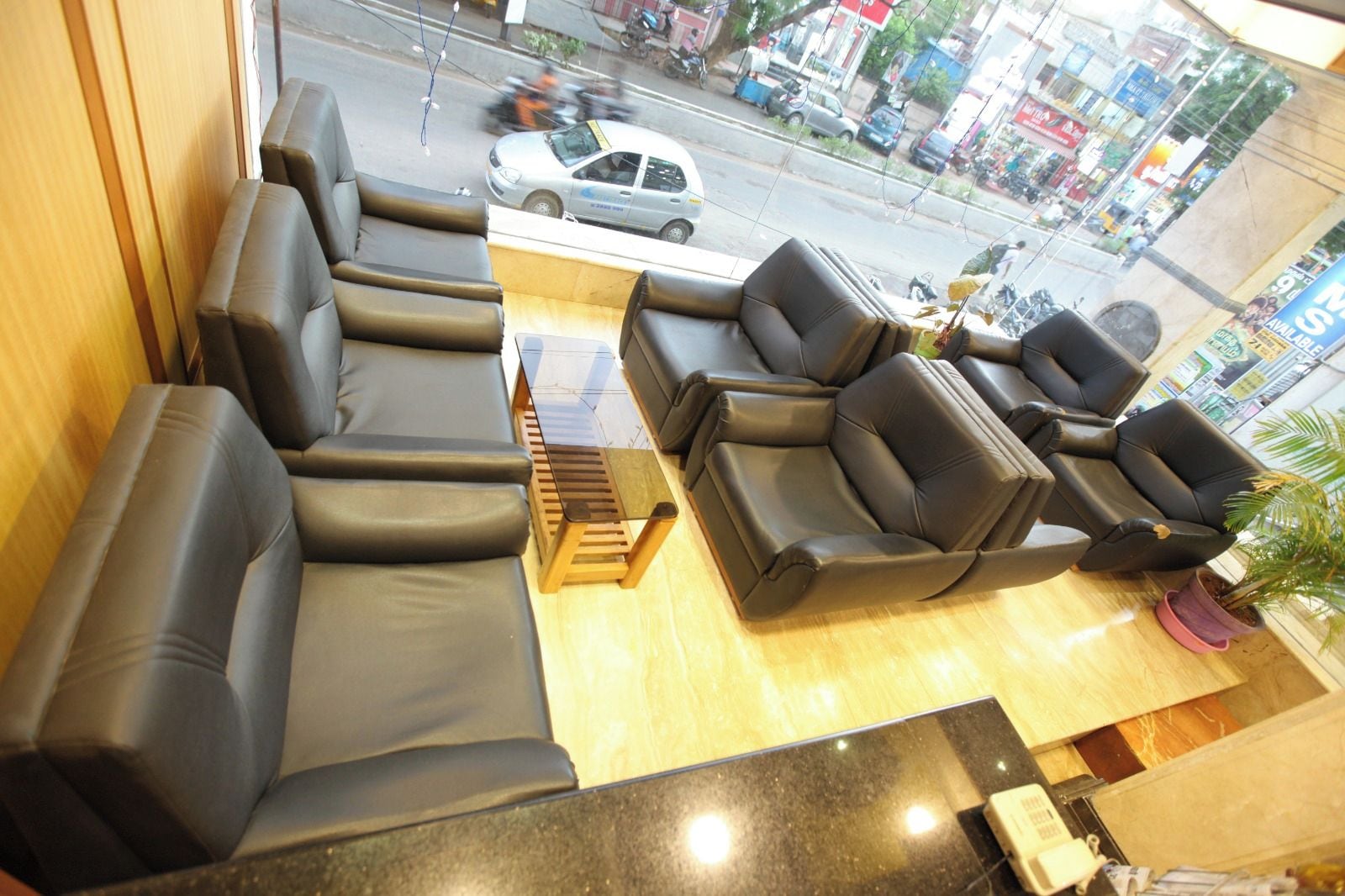 Een zithoek met banken en stoelen, een houten bijzettafeltje en uitzicht op de straat.
